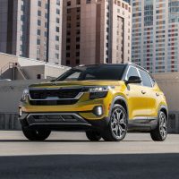 Yellow 2021 Kia Seltos parked among high-rises