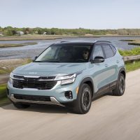 Pluton Blue 2024 Kia Seltos driving by the water